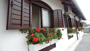 A building with multiple windows, some with shutters, and flower boxes with red flowers.