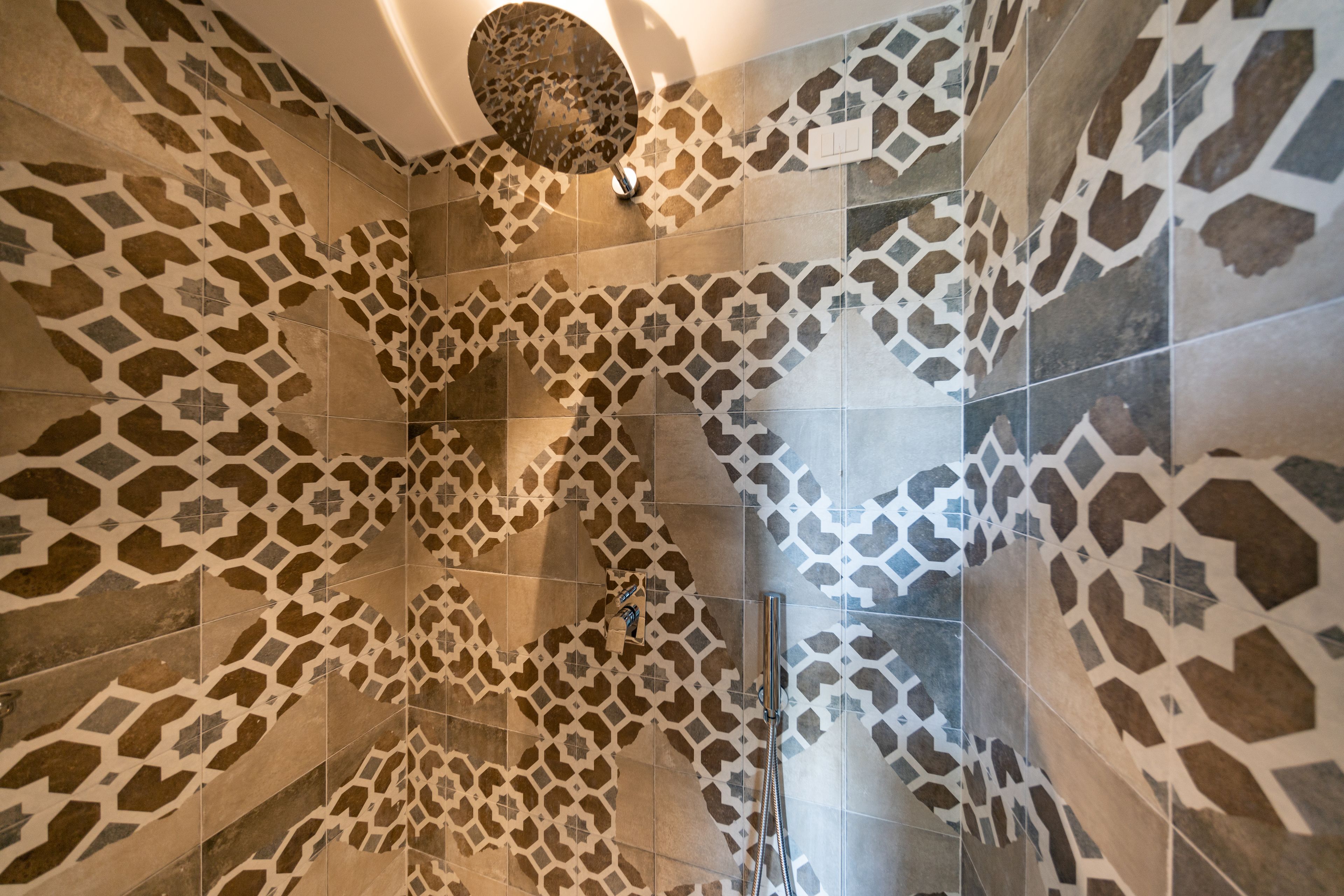 A bathroom with patterned tiles and a shower area.