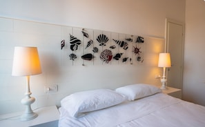 A hotel room with a bed, two bedside lamps, and a wall with a marine-themed artwork. - Marina Garden Hotel (Marciana Marina)