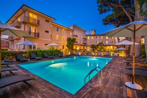 A swimming pool with lounge chairs and umbrellas, surrounded by a wooden deck and a building with balconies. - Marina Garden Hotel (Marciana Marina)