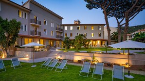 A hotel courtyard with outdoor seating, a pool, and a well-lit building facade. - Marina Garden Hotel (Marciana Marina)