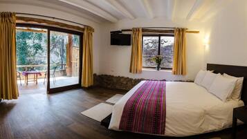 Un dormitorio con una cama grande, un televisor montado en la pared y un balcón con cortinas.