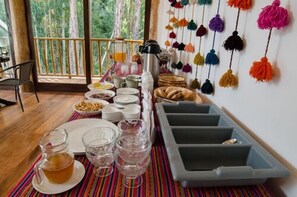 Spiseområde med buffet, kaffestation og farverige hængende dekorationer.