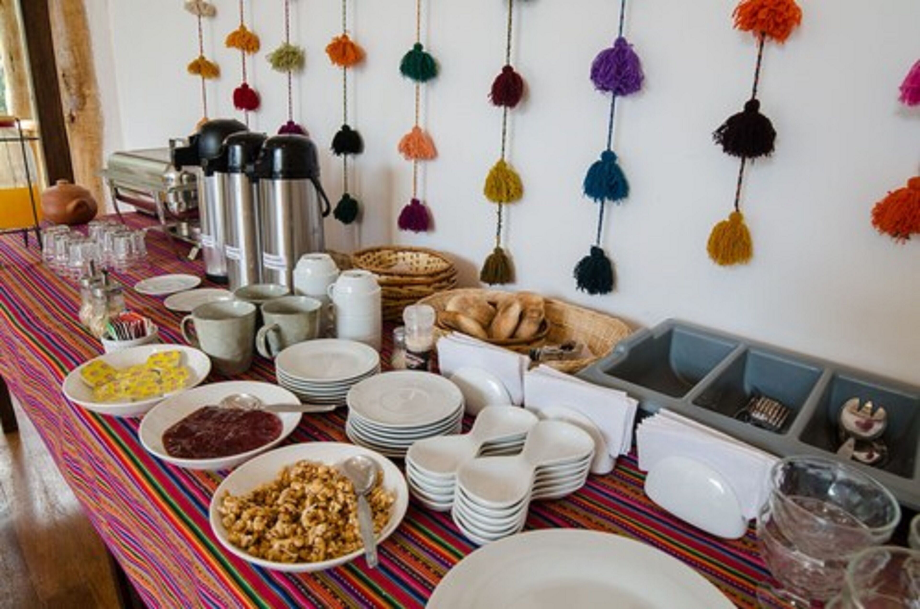 Un bufé de desayuno con diversos platos, máquinas de café y adornos colgantes.