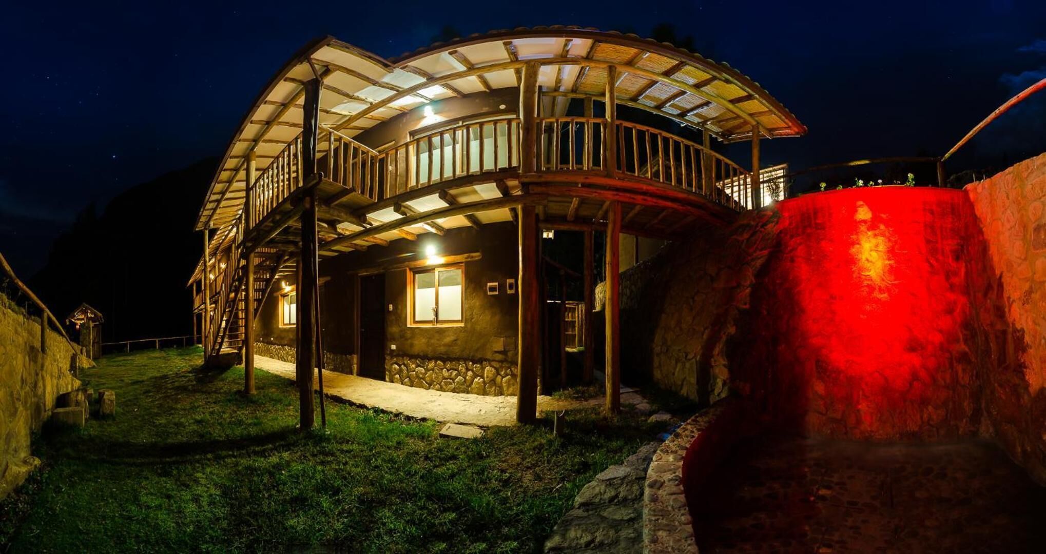 Una casa de madera con balcón y pared de piedra.
