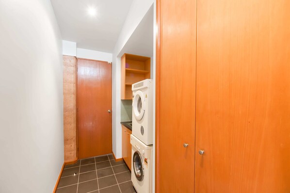 A laundry room with a washing machine and dryer, wooden cabinets, and a tiled floor.