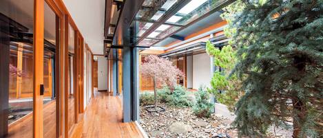 A modern interior with a wooden floor, glass walls, and a garden area with rocks and plants.