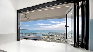 A balcony with a view of a marina and boats, a ceiling fan, and a glass door. - Island Views - the perfect holiday home. Centre of Airlie Beach. (Airlie Beach)