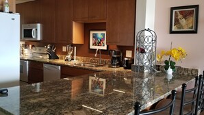Una cucina moderna con piani di lavoro in granito, elettrodomestici in acciaio inossidabile e un espositore metallico decorativo.