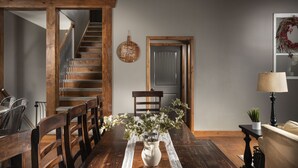 Un'area pranzo con tavolo in legno, sedie, un vaso con fiori, una scala e una porta.