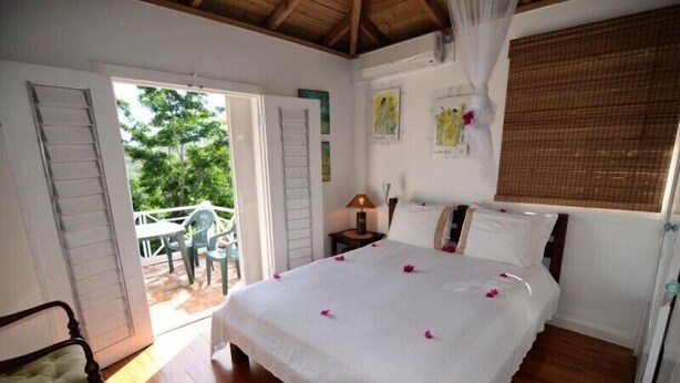 Une chambre à coucher comprenant un lit, une table de chevet, une lampe, une chaise et un balcon avec une table et des chaises.