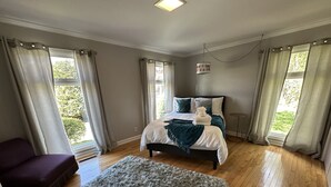 Une chambre à coucher avec un lit, une chaise, un tapis et des rideaux.