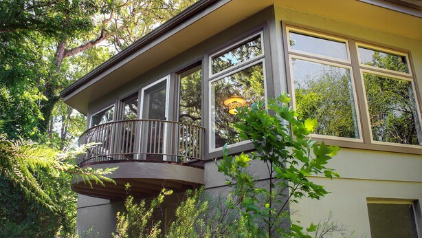 Une maison avec un balcon donnant sur un jardin.