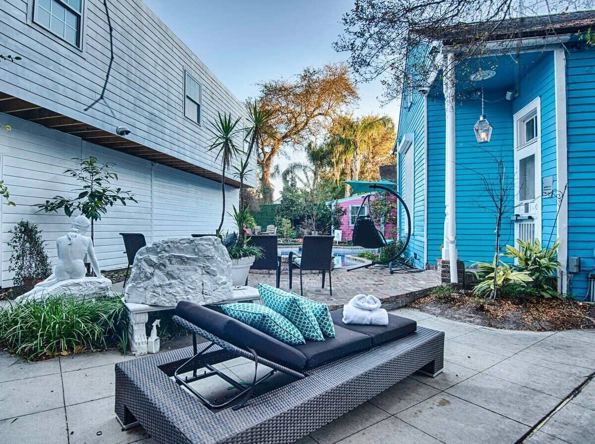 A patio with a black lounge chair, a white statue, and a blue house in the background.