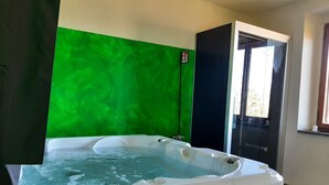 A hot tub in a room with a green wall and a black cabinet. - Ricavo lodge with heated pool and outdoor jacuzzi (Lecchi in Chianti)