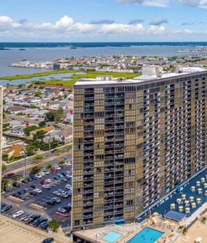 A high-rise hotel with a rooftop pool and a view of the surrounding cityscape.