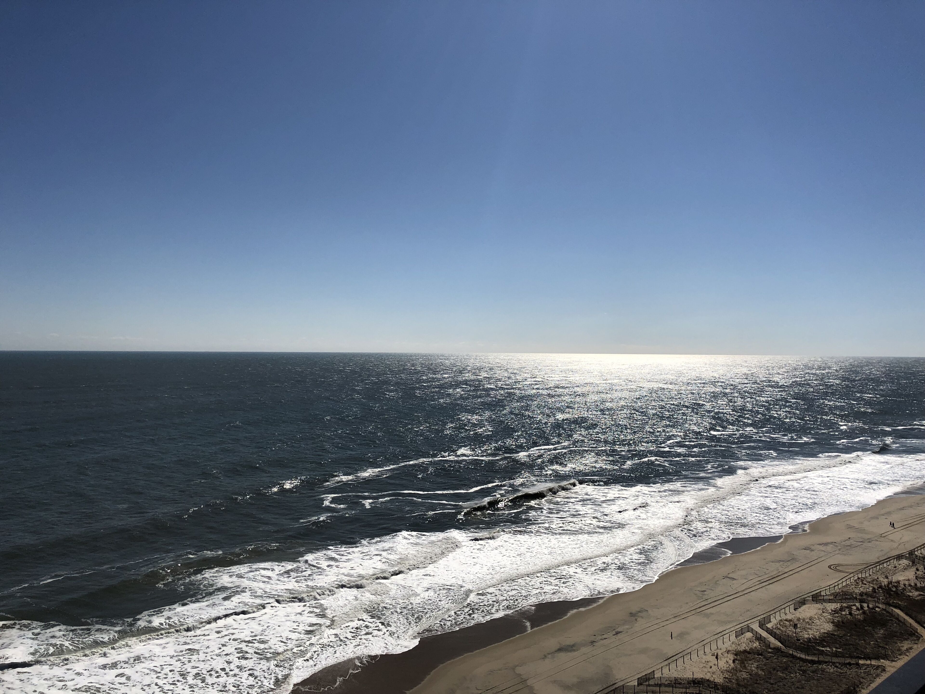 Une plage avec des vagues, un ciel dégagé et un horizon lointain.