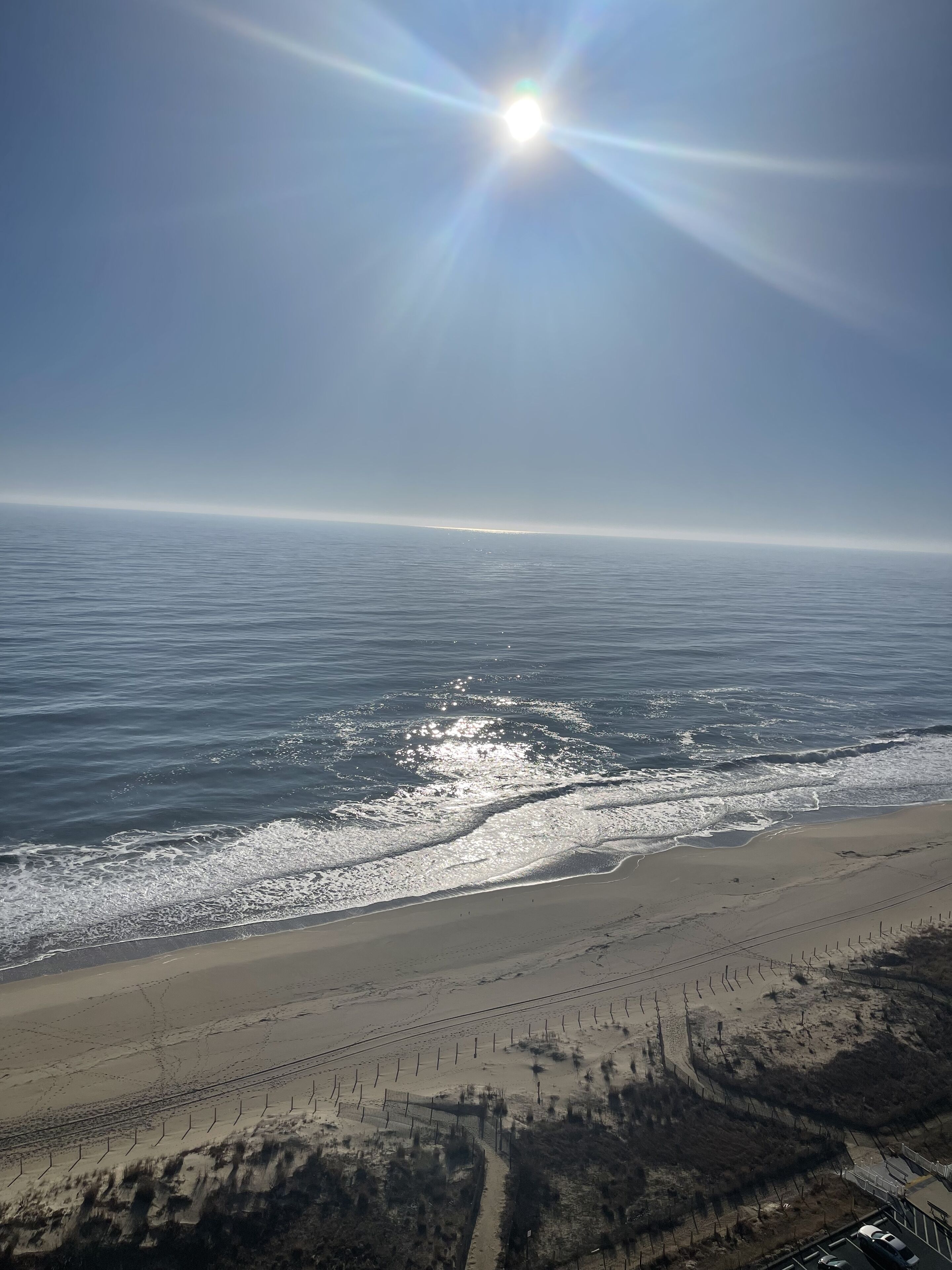 Ein Strand mit einem Zaun und blauem Himmel.