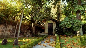A stone pathway leading to a small stone building with a black door, surrounded by lush greenery and trees. - Villa 15 minutes from Porto  (Paredes, Carvalhal)