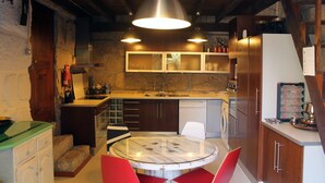 A compact kitchen with a round dining table, wooden cabinets, and a hanging light fixture. - Villa 15 minutes from Porto  (Paredes, Carvalhal)