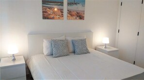 Relax in this serene bedroom with a large bed, two bedside tables, and framed beach views.
