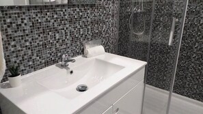 A bathroom with a white sink, a roll of toilet paper, and a potted plant. - TORRE 17- City View, Wifi, Cozy and Refurbished (Quarteira)