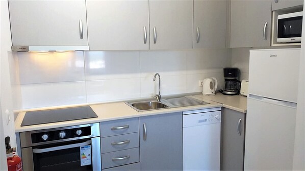 A compact kitchen with a built-in oven, a dishwasher, a microwave, and a coffee maker. - TORRE 17- City View, Wifi, Cozy and Refurbished (Quarteira)