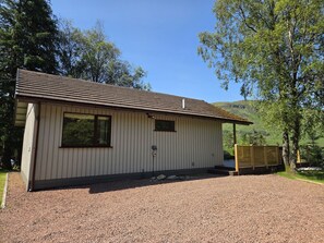 En enplansbyggnad med ett sluttande tak, en grusuppfart och ett trästaket.