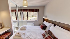 Un dormitorio con cama, mesita de noche y ventana con vista a la carretera.