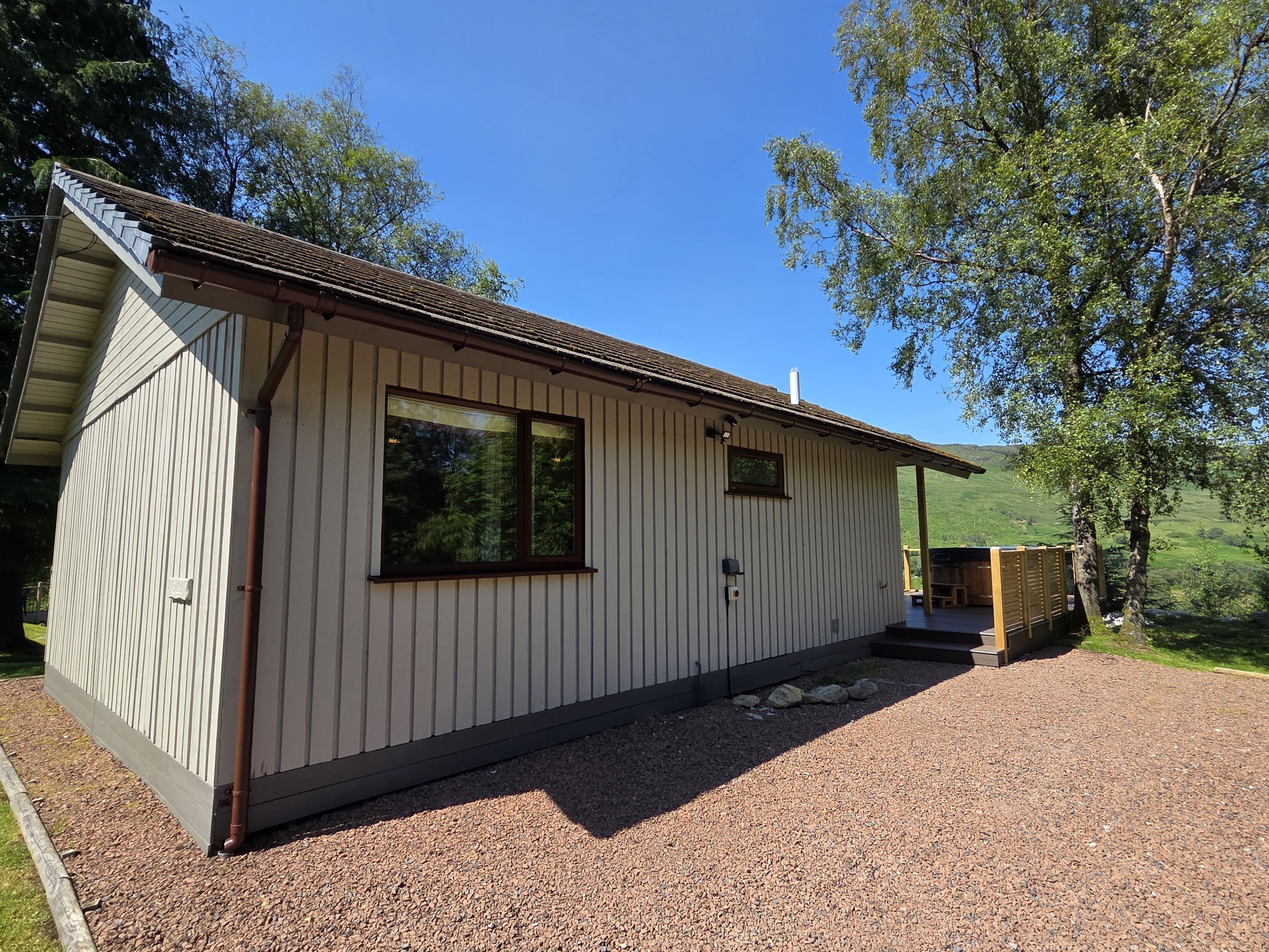 A single-story building with a sloped roof, a large window, and a gravel driveway.