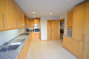 Kitchen area with oven, stainless steel sink, and granite countertop.
