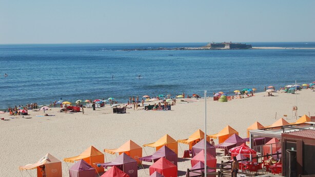 A beach with tents and umbrellas, a sandy shore, and a body of water. - Beach House - 1st Floor (Moledo)
