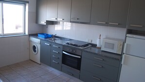 A modern kitchen with grey cabinets, a washing machine, a microwave, and a dishwasher. - Beach House - 1st Floor (Moledo)