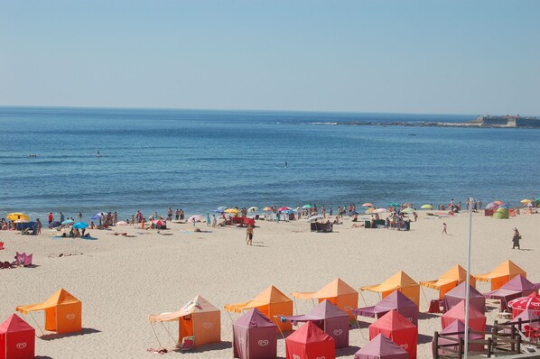 Une plage avec des tentes et des parasols, des gens qui se détendent et un ciel dégagé.