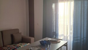 A dining area with a table set for two, a sofa, and a hanging light fixture. - Beach House - 1st Floor (Moledo)