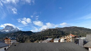 Un pueblo de montaña con edificios tradicionales y un pico montañoso destacado al fondo.