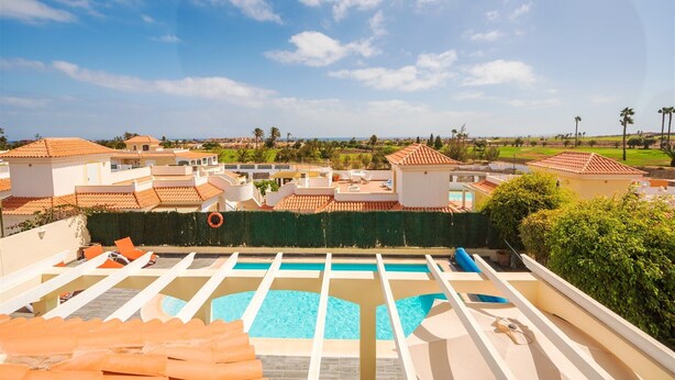 Un área de piscina en la azotea con múltiples sillones de descanso y una piscina.