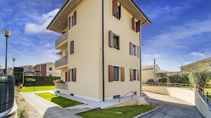 A multi-story residential building with a flat roof, multiple windows, and a small front yard with a pathway leading to the entrance. - Residence San Zeno 3, Bardolino ,WI-FI, AC, park (Bardolino)