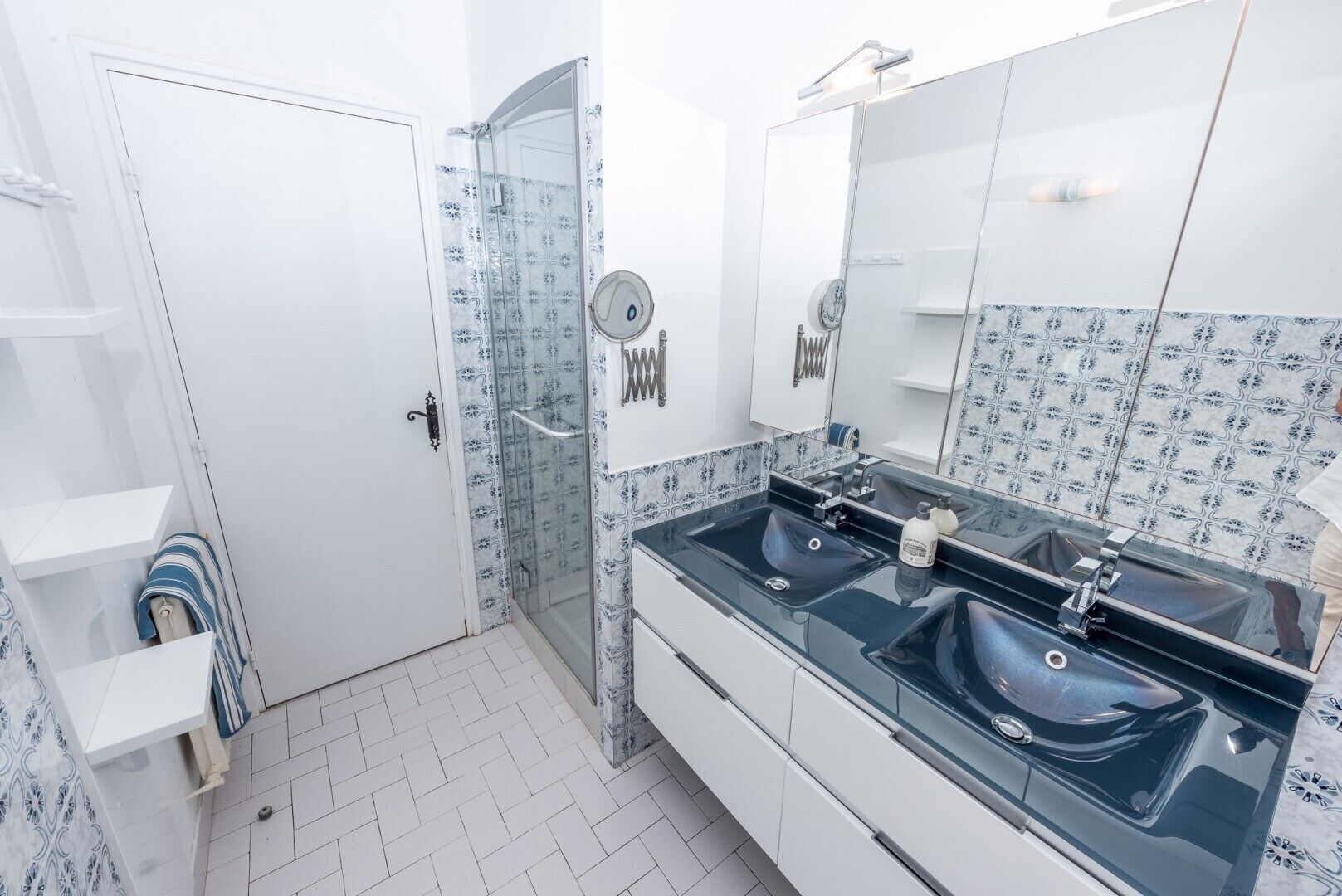 Ein Badezimmer mit zwei Waschbecken, einer Duschkabine aus Glas und einem großen Spiegel.