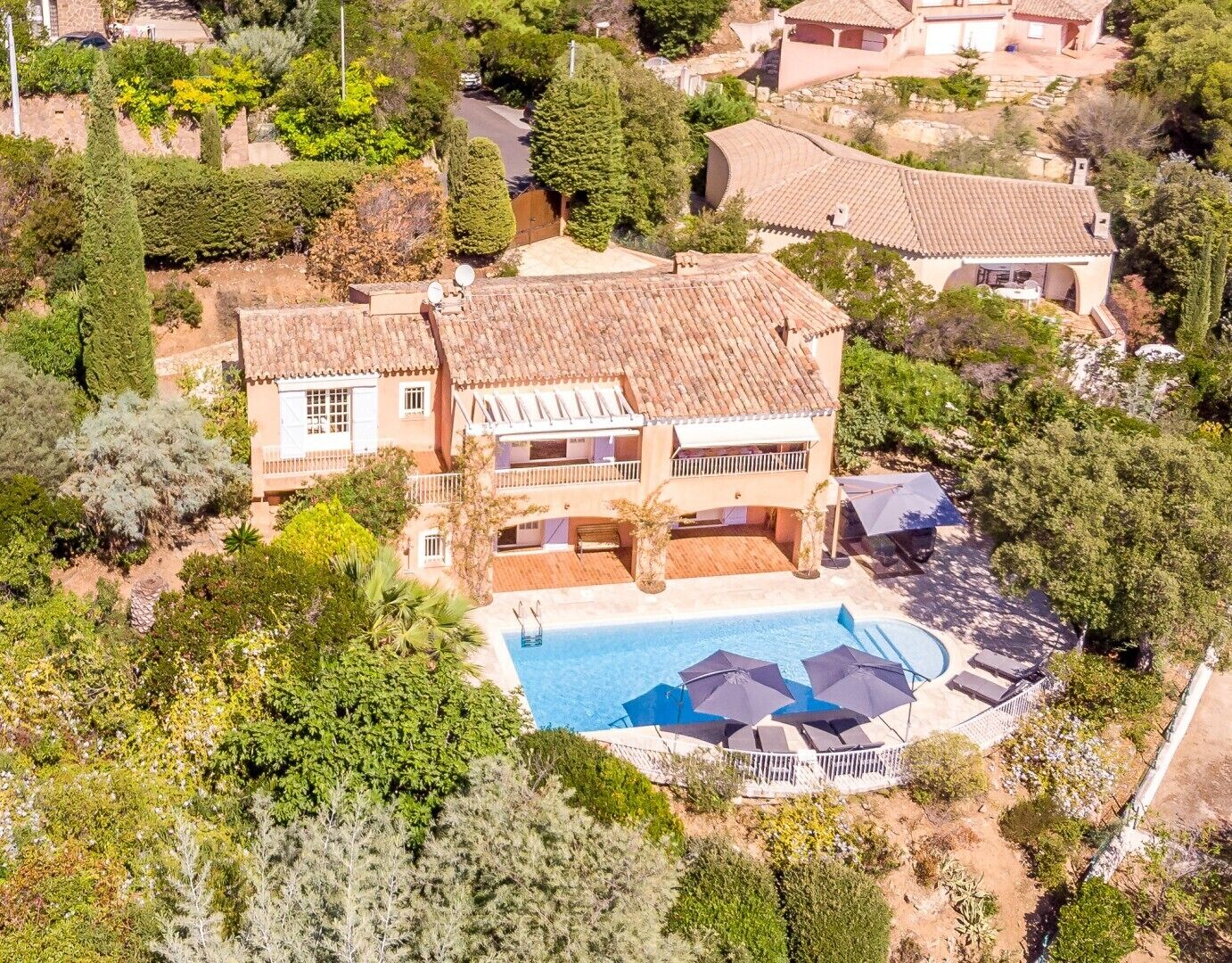 Une grande maison à deux étages avec une piscine et un espace extérieur aménagé pour se détendre.