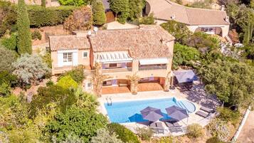 Une grande maison à deux étages avec une piscine et un espace extérieur aménagé pour se détendre.