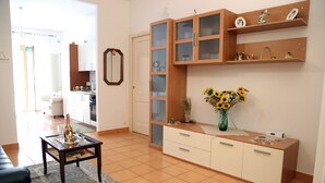 A living room with a sofa, a coffee table, a cabinet, and a vase with flowers.