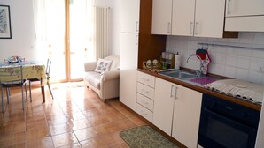 A compact kitchen with white cabinets, a wooden countertop, and a built-in oven.