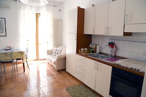 A compact kitchen with white cabinets, a wooden countertop, and a built-in oven.