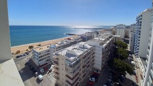 A coastal cityscape with a beach, high-rise buildings, and a clear sky. - TORRE AZUL- Magnificent Sunset, Wifi, 20 m from the Beach (Quarteira)