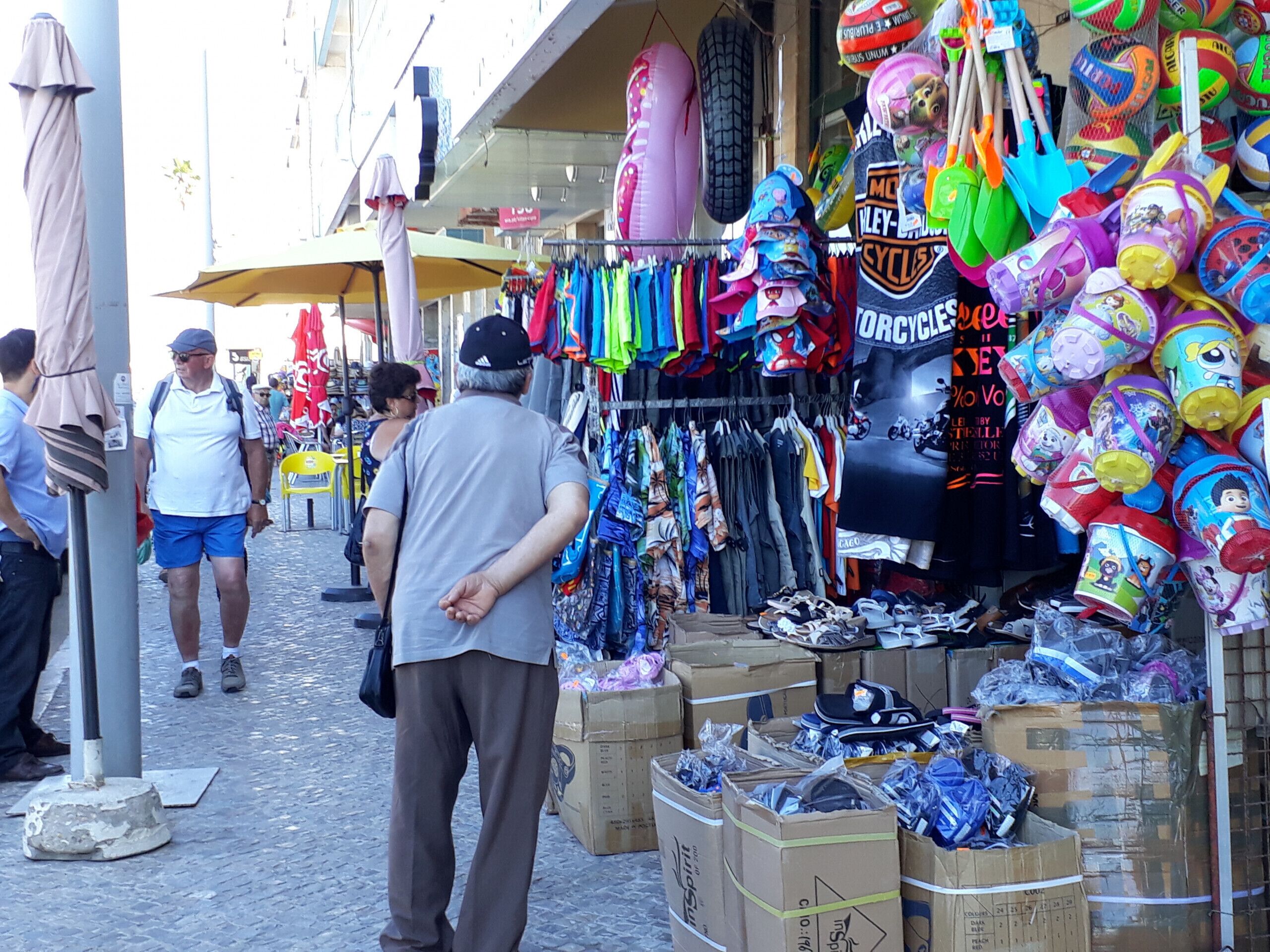 Ein Straßenmarkt mit verschiedenen Ständen, die buntes Strandkleidung und Zubehör anbieten.