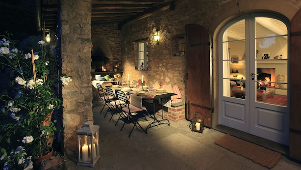 A rustic dining area with a stone wall, wooden beams, and a table set for two.