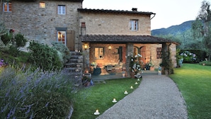 A stone house with a patio, outdoor seating, and a gravel path leading to the entrance.