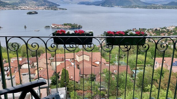 A balcony with a view of a lake, mountains, and a town.