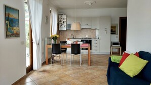 A compact living space with a dining area, kitchenette, and a sofa with colorful cushions.
